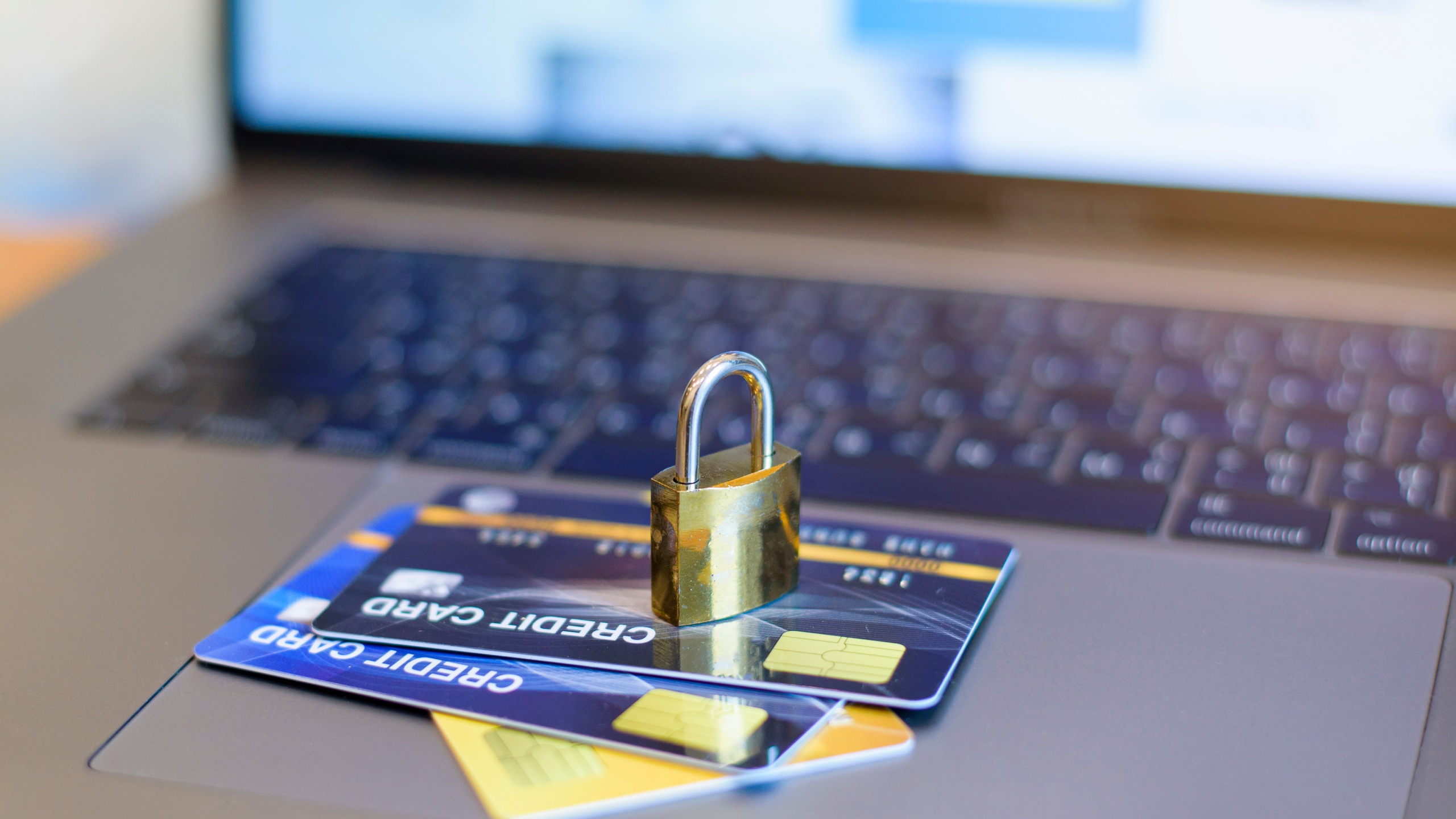 A padlock sits on top of credit cards near a laptop, demonstrating security from elder financial exploitation.